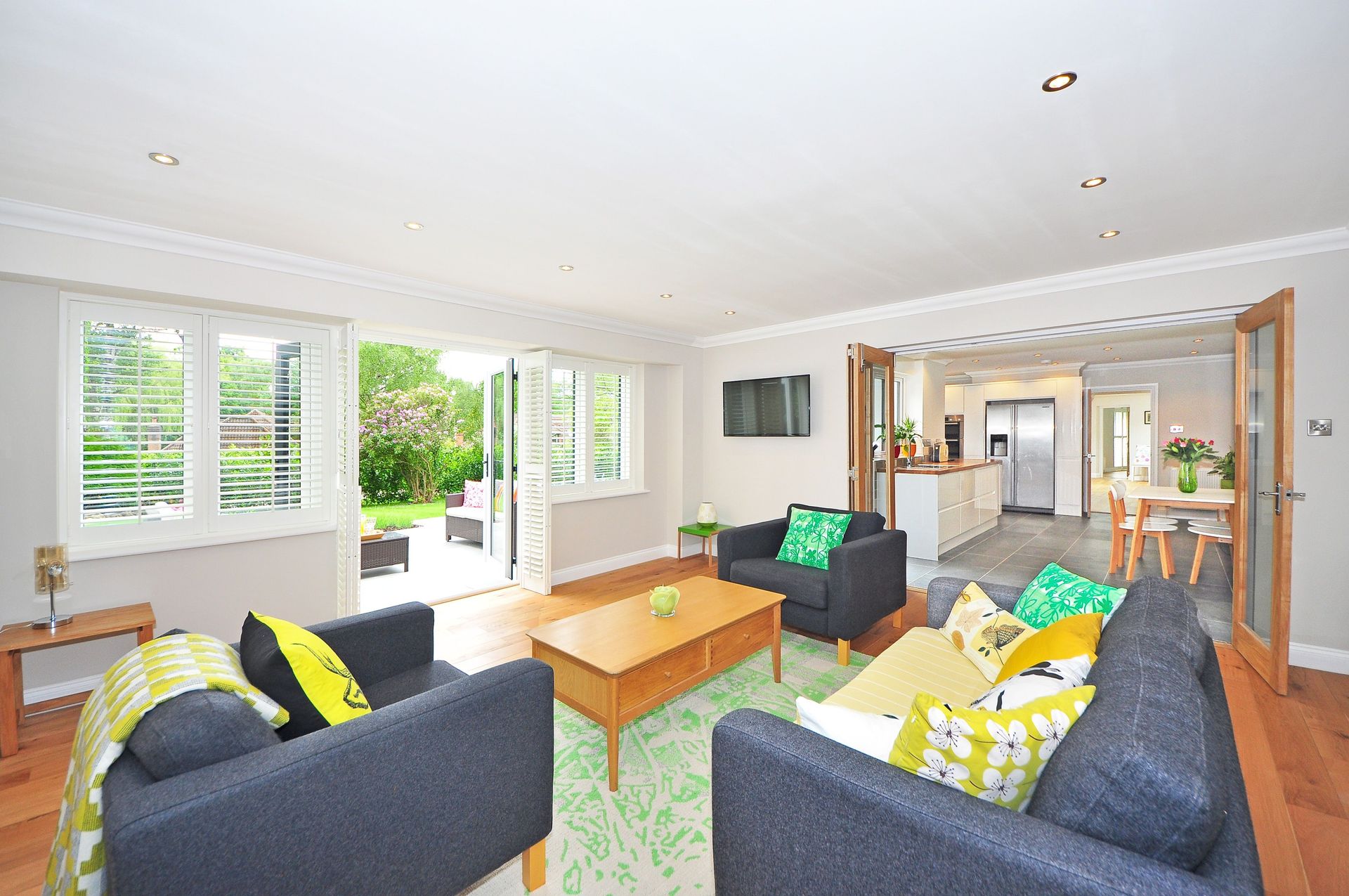 Modern living room with open plan kitchen and garden view, bright and airy ambiance.